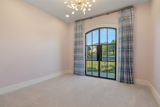 carpeted empty room featuring a notable chandelier