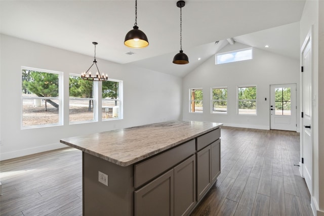 kitchen featuring vaulted ceiling, a wealth of natural light, decorative light fixtures, and hardwood / wood-style floors