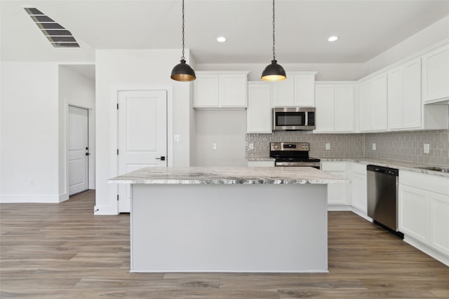 kitchen featuring stainless steel appliances, wood-type flooring, pendant lighting, and a kitchen island