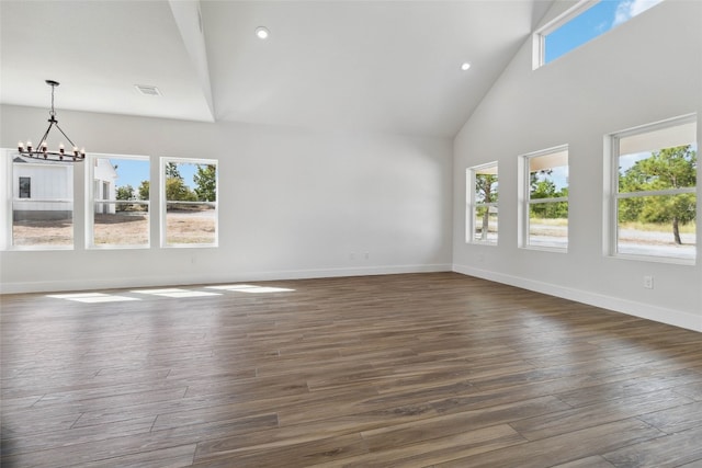 unfurnished living room with a chandelier, dark wood-type flooring, and high vaulted ceiling