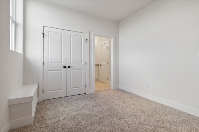 unfurnished bedroom with a closet and light colored carpet