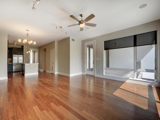 unfurnished living room featuring hardwood / wood-style flooring, sink, and ceiling fan with notable chandelier