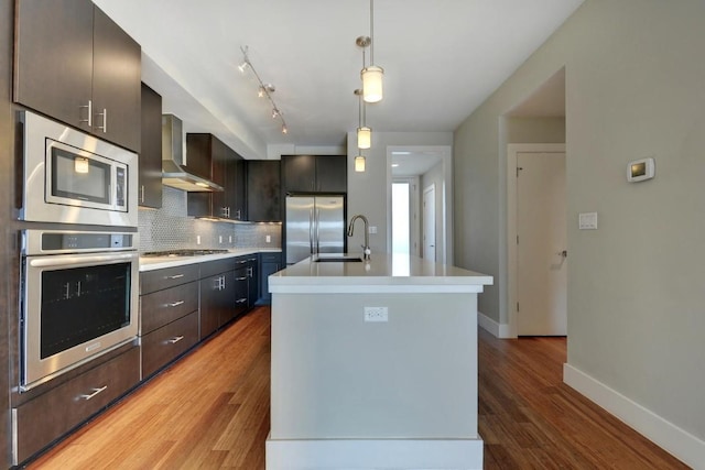 kitchen featuring sink, tasteful backsplash, hanging light fixtures, a center island with sink, and stainless steel appliances