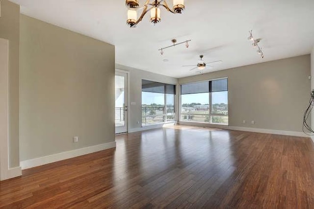 unfurnished room with rail lighting, dark hardwood / wood-style floors, and ceiling fan with notable chandelier