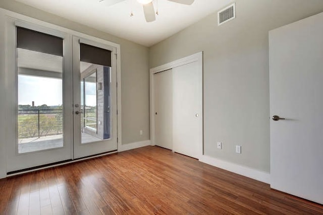 unfurnished bedroom featuring french doors, access to outside, a closet, ceiling fan, and dark wood-type flooring