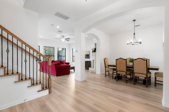 dining space featuring ceiling fan with notable chandelier and light wood-type flooring