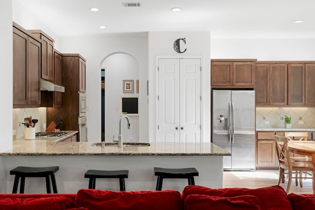 kitchen with sink, kitchen peninsula, decorative backsplash, a breakfast bar, and appliances with stainless steel finishes