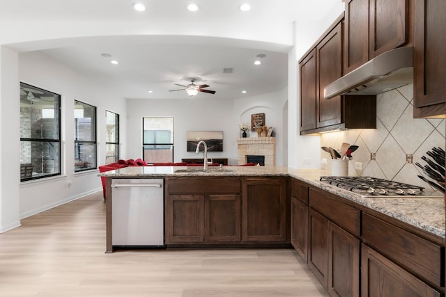 kitchen with kitchen peninsula, sink, light wood-type flooring, and stainless steel appliances