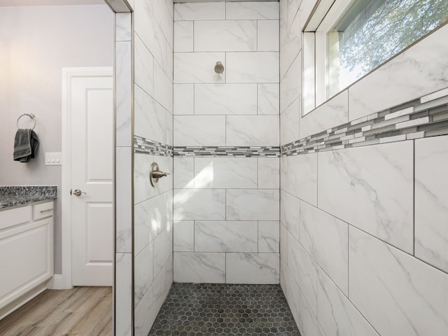 bathroom with vanity, tiled shower, and wood-type flooring