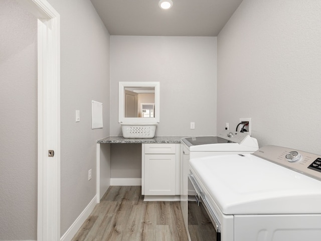 washroom with washer and dryer, cabinets, and light wood-type flooring