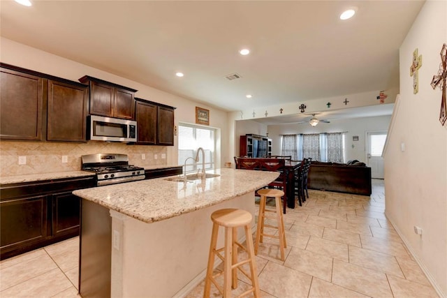 225 Shale Cir, Buda, TX 78610 - kitchen with stainless steel appliances, a sink, a breakfast bar, open floor plan, and light stone counters