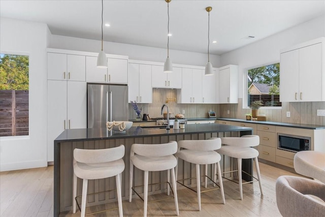 kitchen featuring an island with sink, appliances with stainless steel finishes, sink, and white cabinets