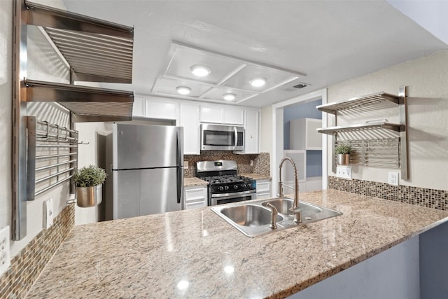 kitchen with sink, backsplash, kitchen peninsula, white cabinetry, and stainless steel appliances