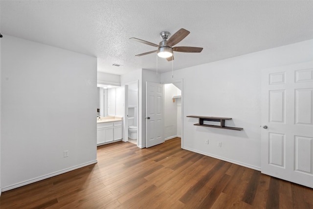 unfurnished bedroom with connected bathroom, sink, dark hardwood / wood-style flooring, a textured ceiling, and ceiling fan