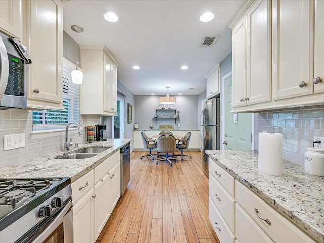 kitchen featuring light hardwood / wood-style floors, white cabinetry, stainless steel appliances, and hanging light fixtures