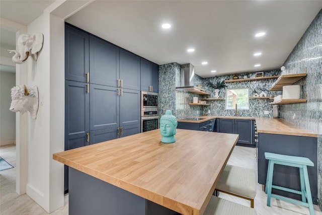 7612 Gault St, Austin, TX 78757 - kitchen featuring stainless steel appliances, wall chimney range hood, butcher block counters, open shelves, and blue cabinets