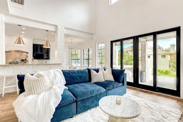 living room featuring a high ceiling, an inviting chandelier, and light hardwood / wood-style flooring