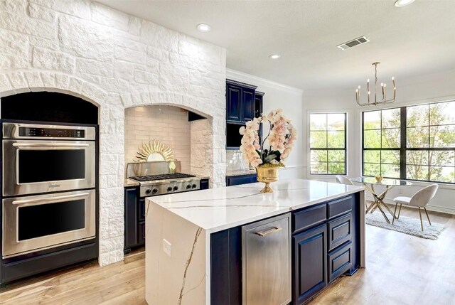 kitchen featuring an inviting chandelier, blue cabinets, ornamental molding, double oven, and a kitchen island