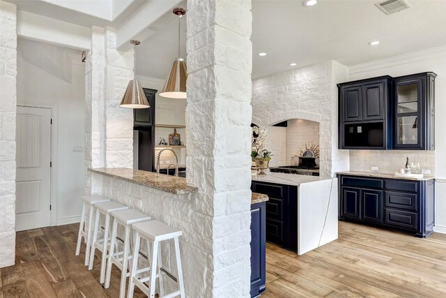 kitchen with light stone countertops, a breakfast bar, light hardwood / wood-style flooring, and kitchen peninsula