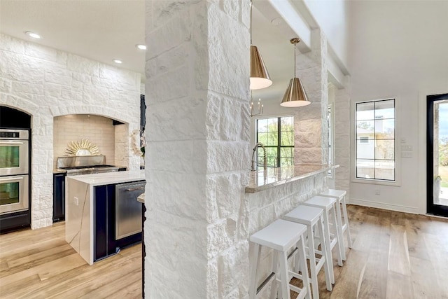 15006 Nightingale Ln, Austin, TX 78734 - kitchen featuring stainless steel appliances, light wood-type flooring, a breakfast bar area, hanging light fixtures, and a towering ceiling