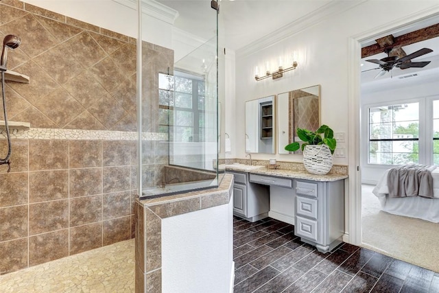 bathroom featuring ceiling fan, tiled shower, ornamental molding, and vanity