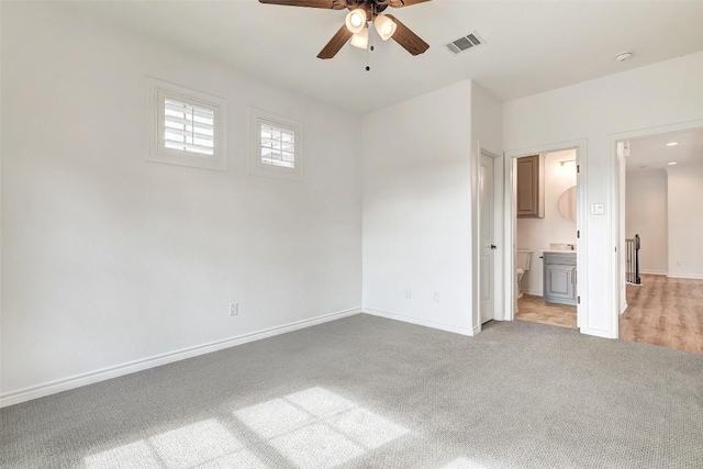 unfurnished bedroom with ceiling fan, light colored carpet, and ensuite bath