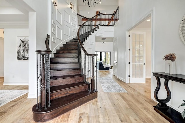 entryway with french doors, ornamental molding, light hardwood / wood-style floors, and a high ceiling