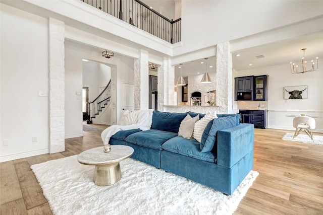 15006 Nightingale Ln, Austin, TX 78734 - living room featuring stairs, light wood-type flooring, a chandelier, a high ceiling, and ornate columns