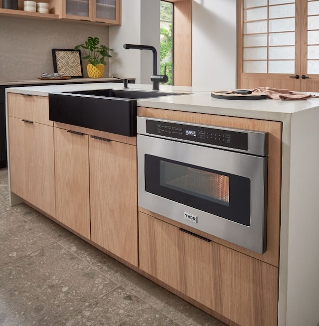 kitchen featuring light brown cabinets, oven, and sink