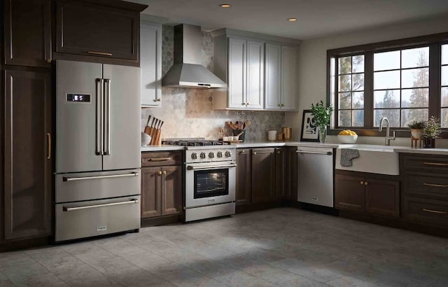 kitchen featuring premium appliances, tasteful backsplash, wall chimney exhaust hood, and sink