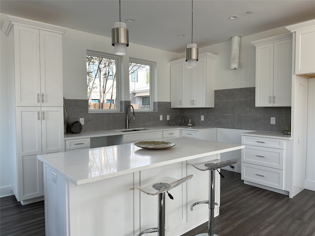 kitchen featuring a center island, decorative light fixtures, white cabinetry, and sink