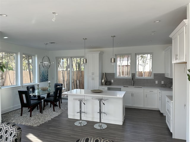 kitchen with white cabinets, a center island, sink, and a wealth of natural light