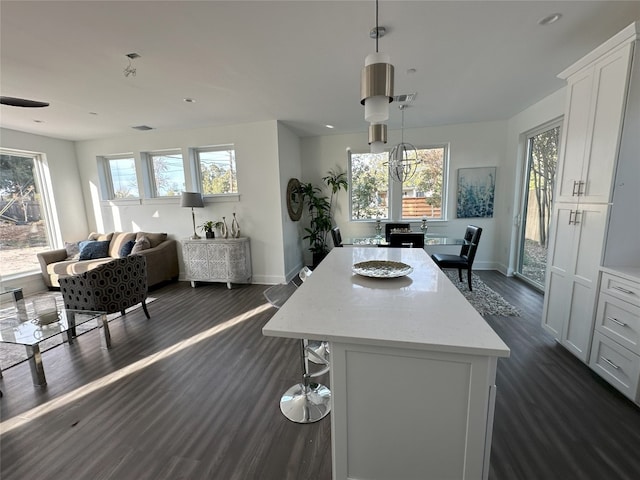 kitchen with plenty of natural light, white cabinets, dark wood-type flooring, and decorative light fixtures