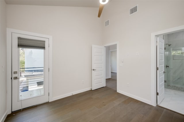 unfurnished bedroom featuring hardwood / wood-style floors, ceiling fan, high vaulted ceiling, and ensuite bath