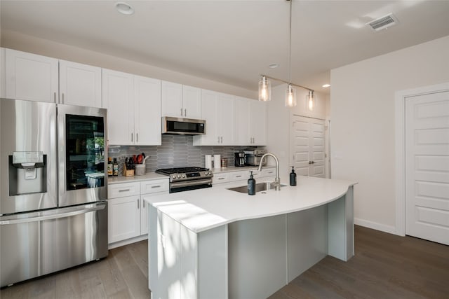 kitchen with a kitchen island with sink, stainless steel appliances, hardwood / wood-style floors, sink, and pendant lighting