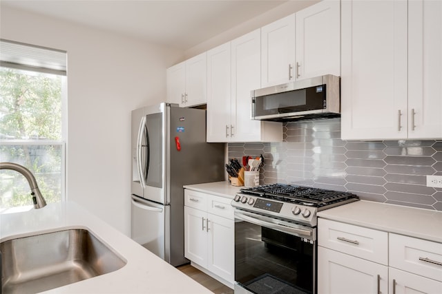 kitchen with stainless steel appliances, sink, and white cabinets