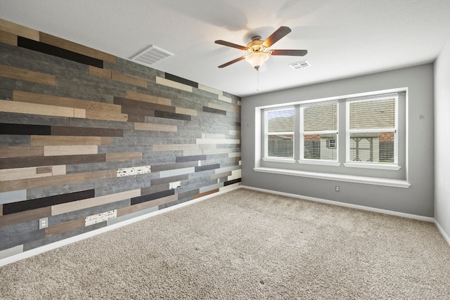 empty room featuring ceiling fan, wood walls, and carpet floors