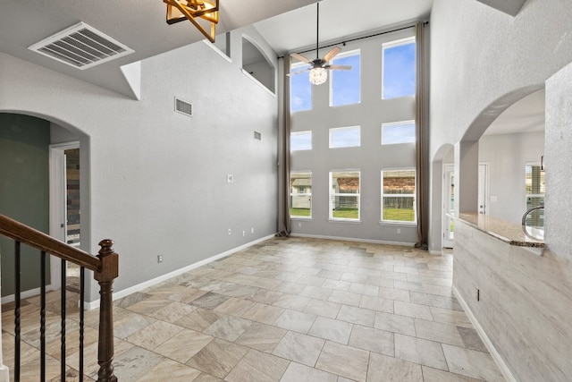 unfurnished living room with ceiling fan and a high ceiling