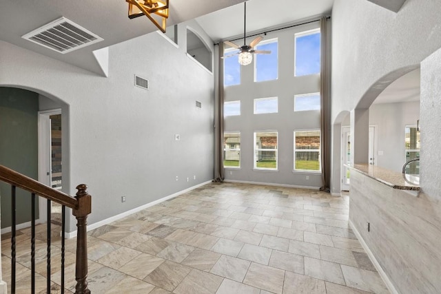 unfurnished living room with plenty of natural light, a ceiling fan, and visible vents