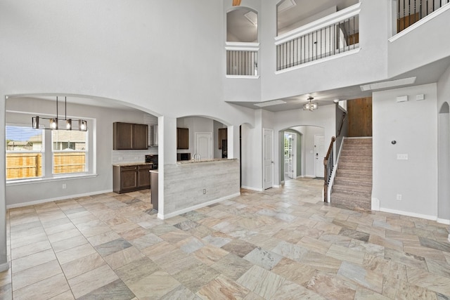 unfurnished living room with a towering ceiling and plenty of natural light