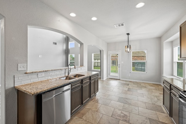 kitchen featuring pendant lighting, sink, appliances with stainless steel finishes, dark brown cabinets, and light stone counters