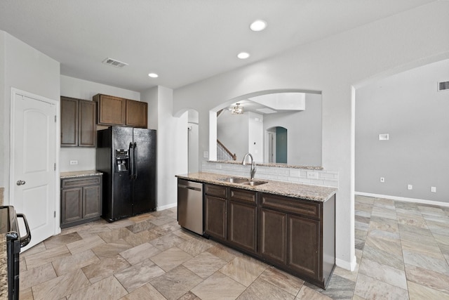 kitchen featuring stainless steel dishwasher, black refrigerator with ice dispenser, sink, range with electric stovetop, and light stone countertops