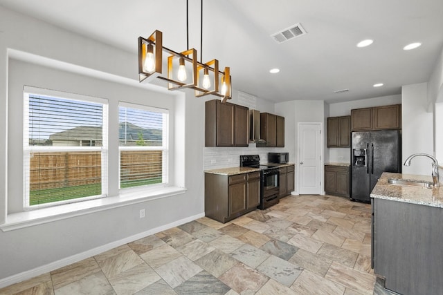 kitchen featuring light stone counters, sink, pendant lighting, and black appliances