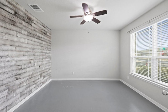 424 Hendelson Ln, Hutto, TX 78634 - empty room featuring an accent wall, healthy amount of natural light, wood walls, ceiling fan, and finished concrete flooring