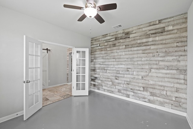 unfurnished room featuring ceiling fan, concrete floors, a barn door, and french doors