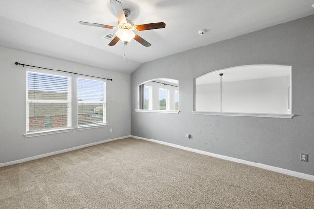 carpeted spare room featuring baseboards, visible vents, ceiling fan, and vaulted ceiling
