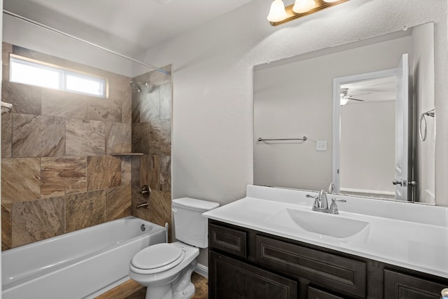 full bathroom featuring toilet, tiled shower / bath combo, ceiling fan, and vanity