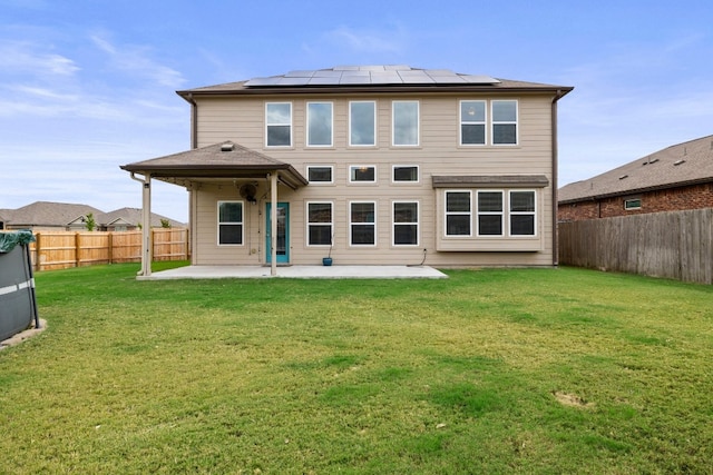 rear view of house with a lawn, solar panels, and a patio