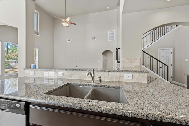 kitchen with light stone countertops, high vaulted ceiling, tasteful backsplash, and sink