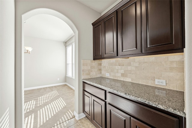 kitchen featuring light stone counters, tasteful backsplash, and dark brown cabinets